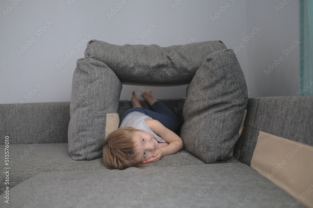 funny European child playing with pillows on couch funny European child playing with pillows on couch