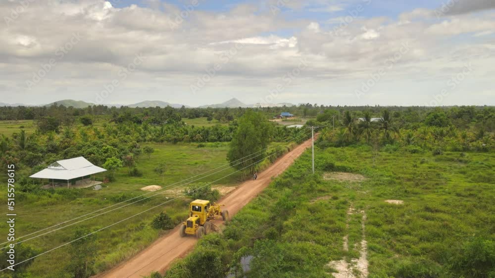 Aerial static view of a road grader widening side of the rural road in the countryside Aerial static view of a road grader widening side of the rural road in the countryside