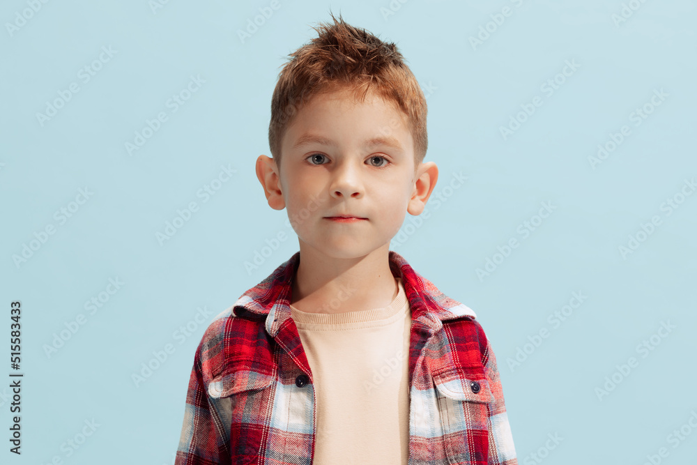 Portrait of little boy, child in checkered shirt looking at camera, posing isolated on blue background Portrait of little boy, child in checkered shirt looking at camera, posing isolated on blue background