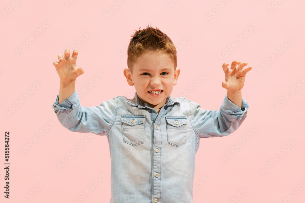 Portrait of little boy, child in jeans t-shirt posing, making faces isolated over pink background Portrait of little boy, child in jeans t-shirt posing, making faces isolated over pink background