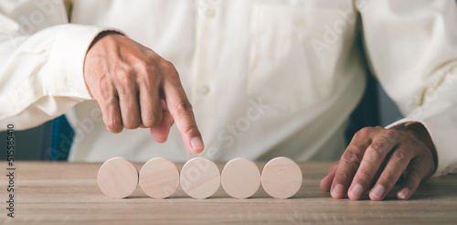 A young businessman pointing to a wooden block