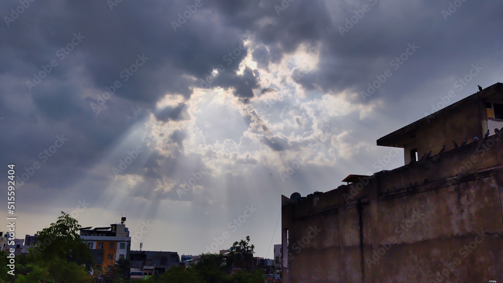 Picture of white and grey clouds in blue sky with sun rays coming from background shot in evening
