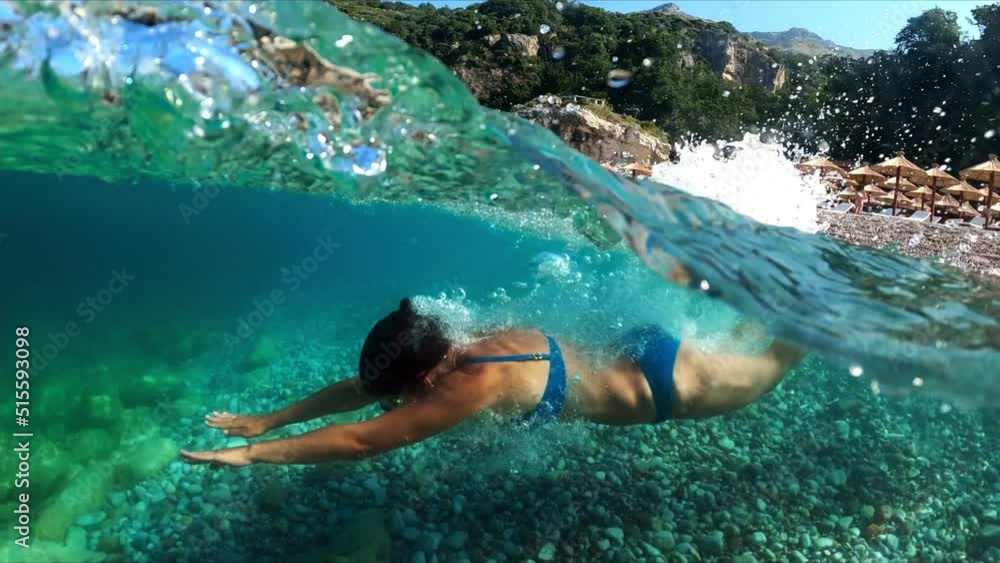 Slow-motion half underwater video at the border of air and water. Beautiful girl dives into the sea of the Montenegro coast. Slow-motion half underwater video at the border of air and water. Beautiful girl dives into the sea of the Montenegro coast.