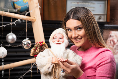 Smiling woman in pink sweater holding a Santa Claus toy
