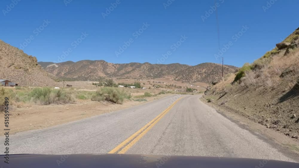 Driving along a country road in the Mojave Desert with a view of the sun damaged view of the car Driving along a country road in the Mojave Desert with a view of the sun damaged view of the car