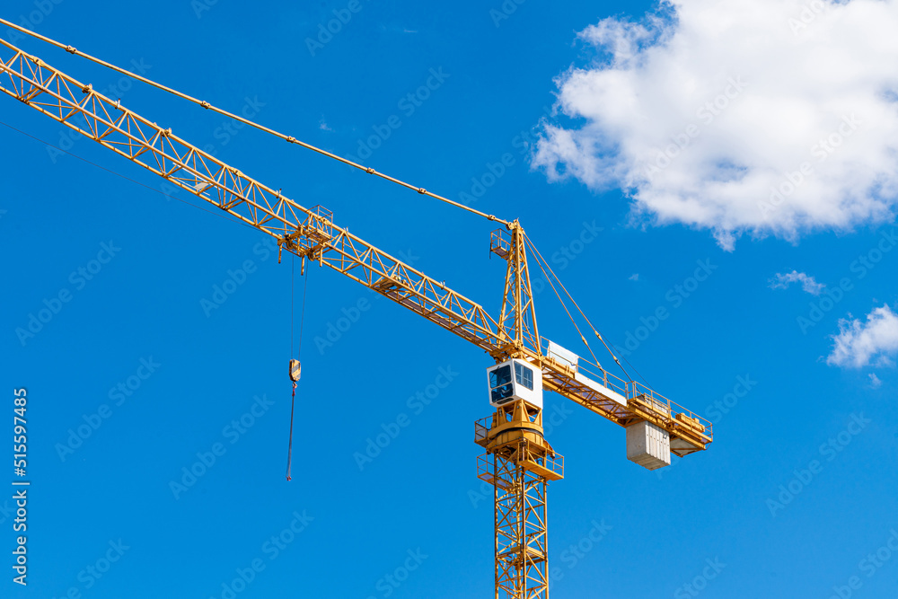Yellow tower crane with white cab against blue sky. Yellow tower crane with white cab against blue sky.