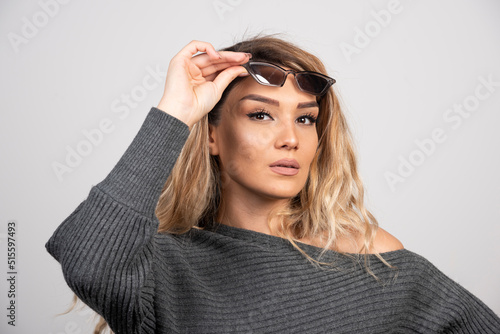 Charming woman in eyeglasses standing on gray background