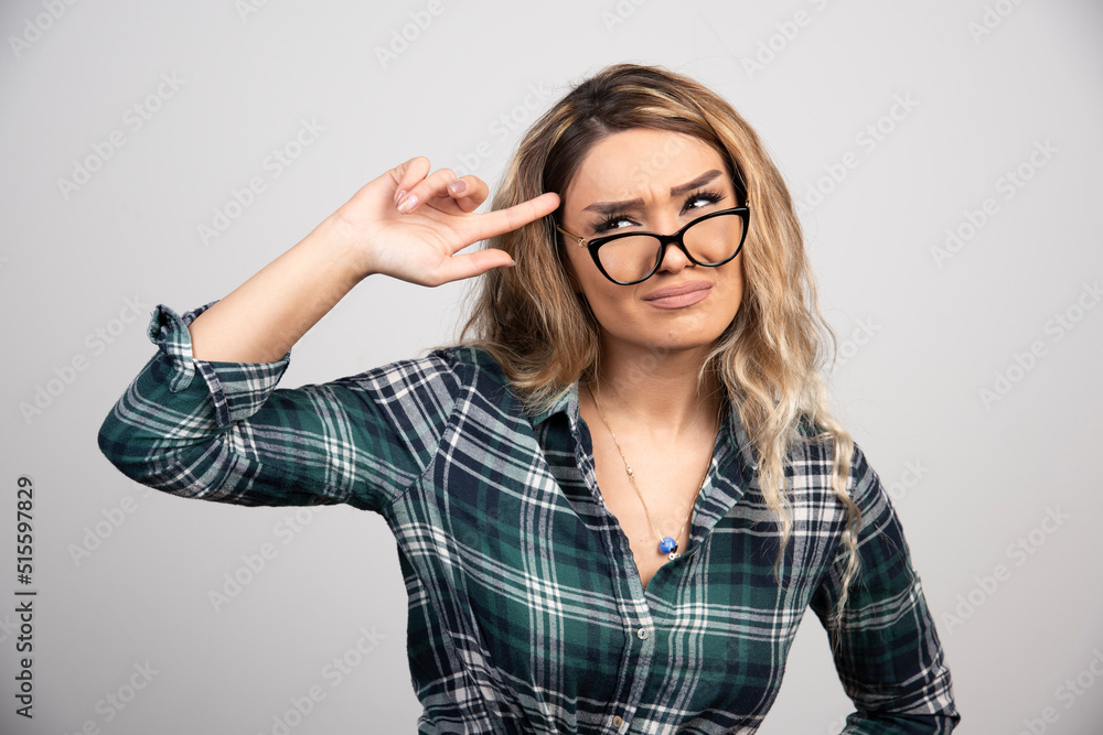Portrait of young woman holding glasses against gray background