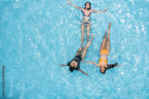 Three women in bikinis floating in a sunny summer swimming pool © Hector Pertuz