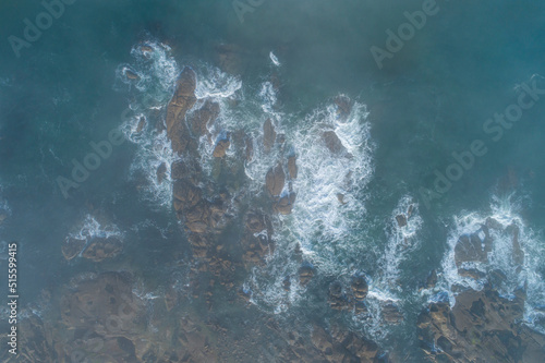 aerial view of some waves on the rocky shore