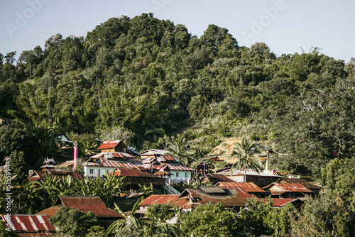 Hsipaw, Myanmar - November 29th, 2019 : view on a remote burmese village in the Shan state near Hsipaw. Colorful tin roofs surrounded by tropical trees photo