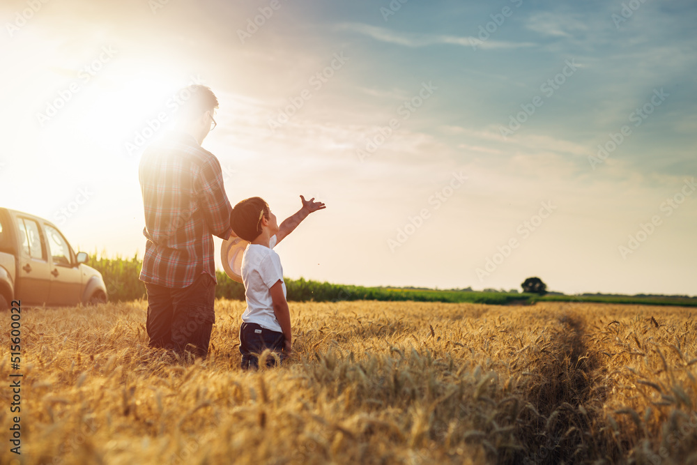 father and son outdoor on wheat field. farmers life concept. father showing their land to his son father and son outdoor on wheat field. farmers life concept. father showing their land to his son