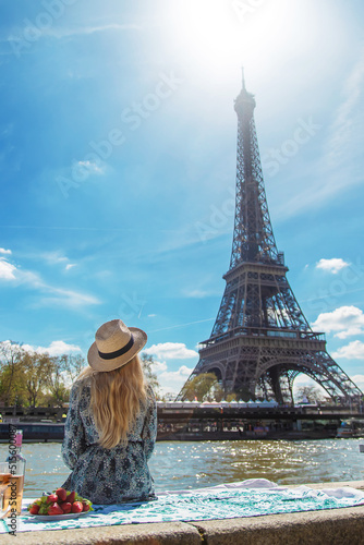 Canvas Print A woman near the Eiffel Tower drinks wine. Selective focus.