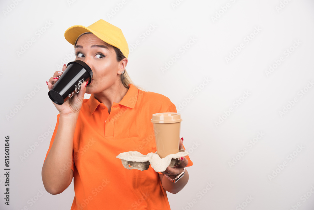 Blonde female courier drinking cup of coffee on white background Blonde female courier drinking cup of coffee on white background