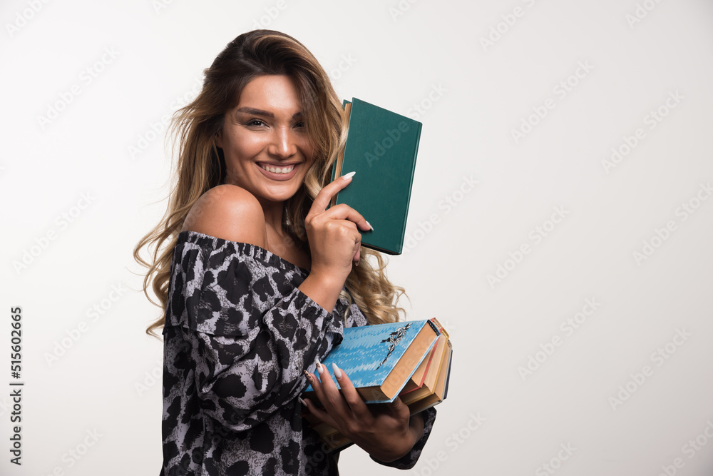 Young woman holding books while laughing on white background Young woman holding books while laughing on white background