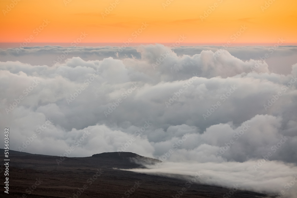 The sun rising over the clouds which line Mount Kilimanjaro.