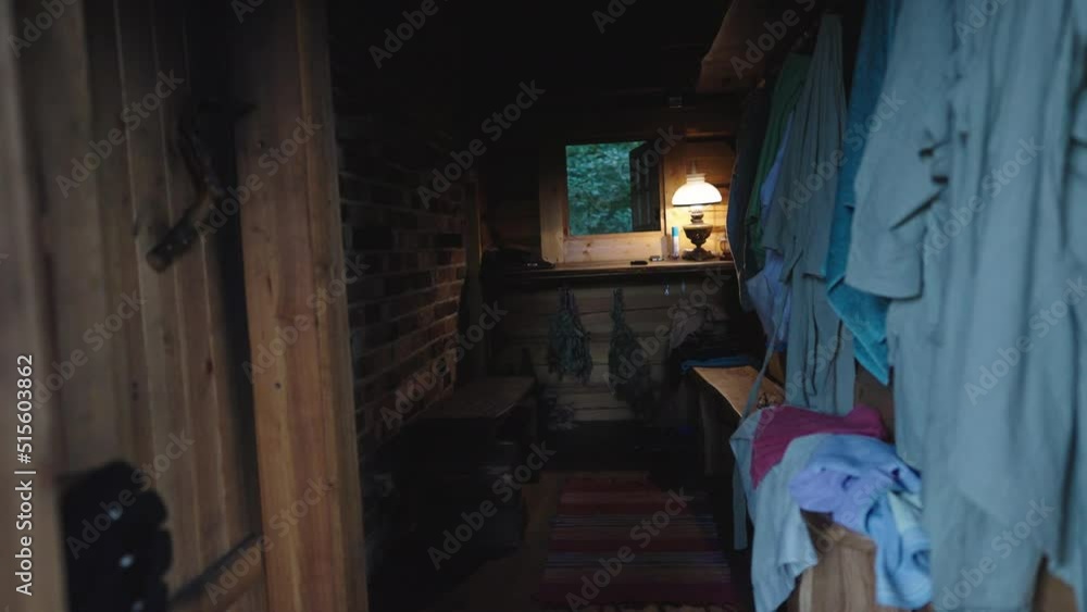 Dark Traditional Wooden Sauna Spa Cabin Room, Relaxing Room, Wooden Bench and Hanging Towels along the Brick Wall, Lamp and Window at the Back Dark Traditional Wooden Sauna Spa Cabin Room, Relaxing Room, Wooden Bench and Hanging Towels along the Brick Wall, Lamp and Window at the Back
