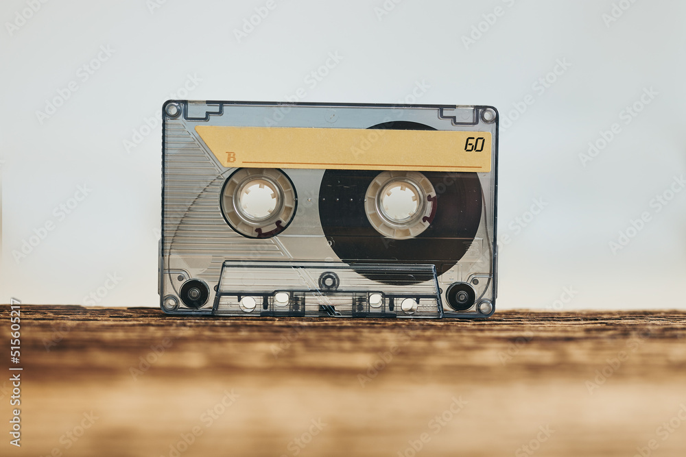 Naklejka premium Tape cassette. Magnetic cassette tape on wooden table. Retro music style. 80s music party. Vintage style. Analog equipment. Stereo sound. Back to the past