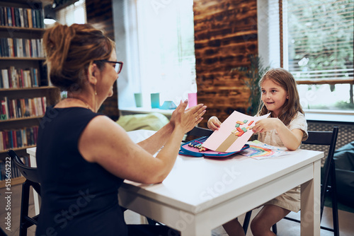 Woman teaching schoolgirl during classes at primary school. Child doing work sitting at desk in afterschool club. Learning at primary school. Elementary education. Back to school