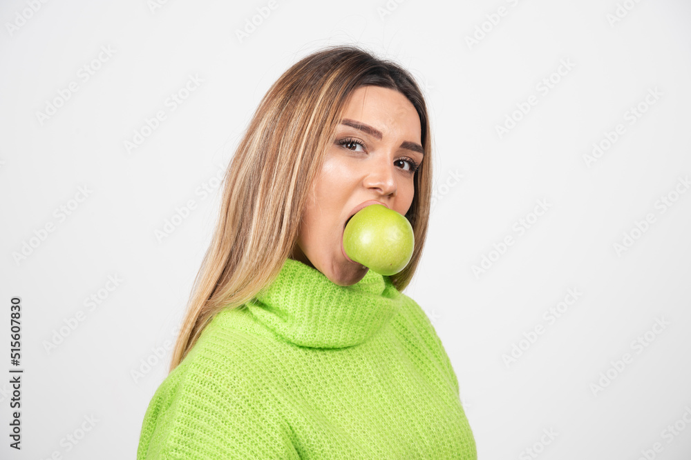 Young woman in green t-shirt eating an apple Young woman in green t-shirt eating an apple