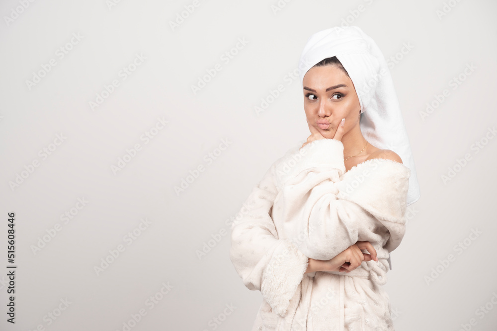 Beautiful young woman in a white bathrobe posing on a white wall Beautiful young woman in a white bathrobe posing on a white wall