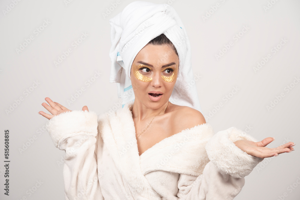 Young woman in bathrobe and cosmetic eye patches posing Young woman in bathrobe and cosmetic eye patches posing