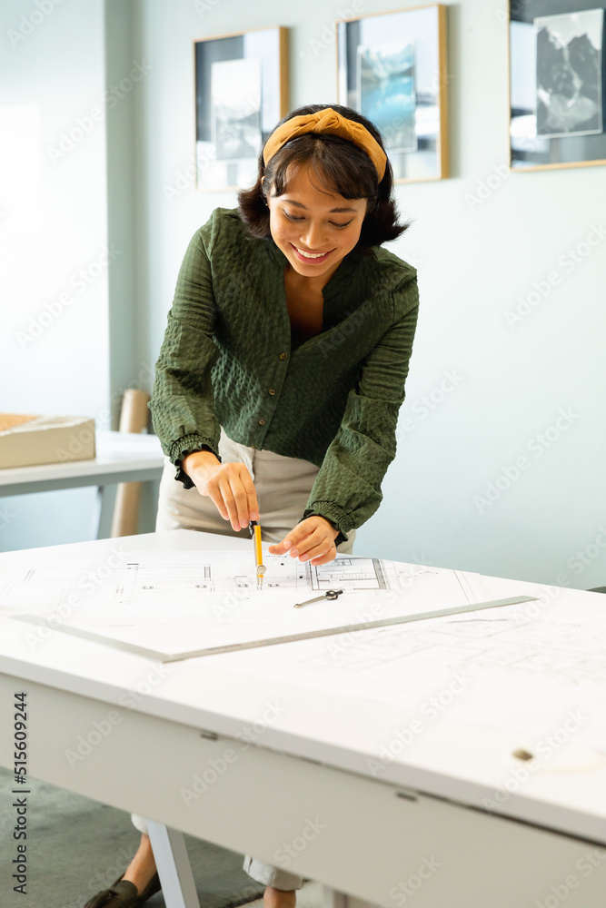 Smiling asian young female architect drawing blueprint at table in creative office Smiling asian young female architect drawing blueprint at table in creative office
