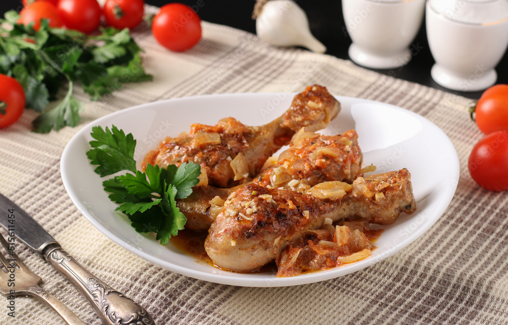 Baked chicken drumsticks with vegetables, spices and parsley on white plate Baked chicken drumsticks with vegetables, spices and parsley on white plate
