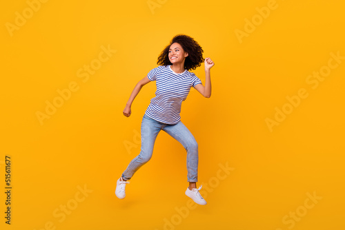 Full body portrait of overjoyed cheerful sporty lady jump run hurry fast isolated on yellow color background