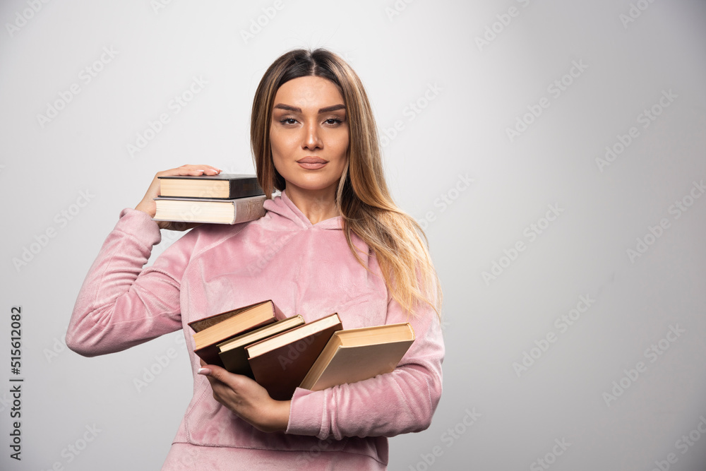 Girl in pink swaetshirt holding her books over her shoulder Girl in pink swaetshirt holding her books over her shoulder