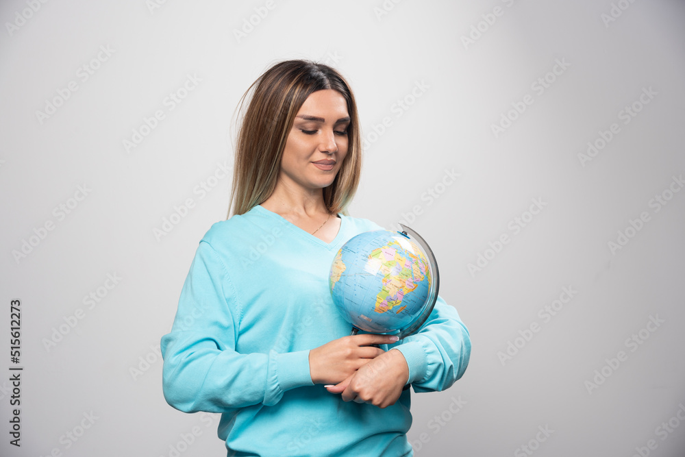 Blonde girl in blue sweatshirt holding a globe, guessing location and having fun Blonde girl in blue sweatshirt holding a globe, guessing location and having fun