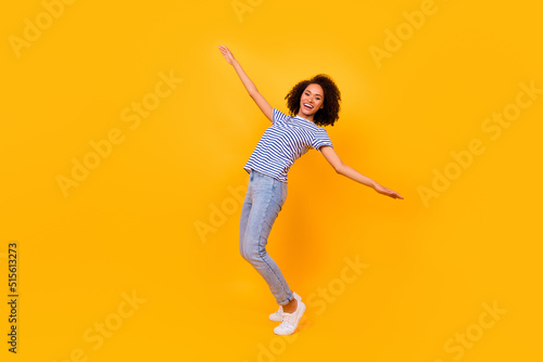Full length portrait of overjoyed positive lady stand tiptoe enjoy good mood isolated on yellow color background © deagreez