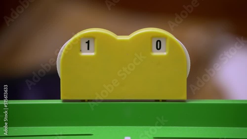 Close-up of a players hand updating the score on a plastic board game scoreboard. Gameplay, competition, user engagement. Leisure activity, tabletop games, board games, family games.
