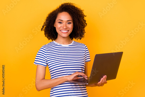 Portrait of charming positive lady toothy smile hands hold wireless netbook isolated on yellow color background