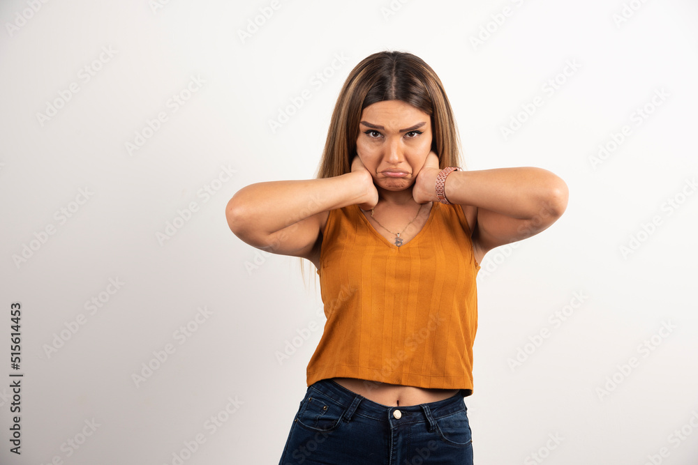Upset woman putting hands on her neck and posing on white background Upset woman putting hands on her neck and posing on white background