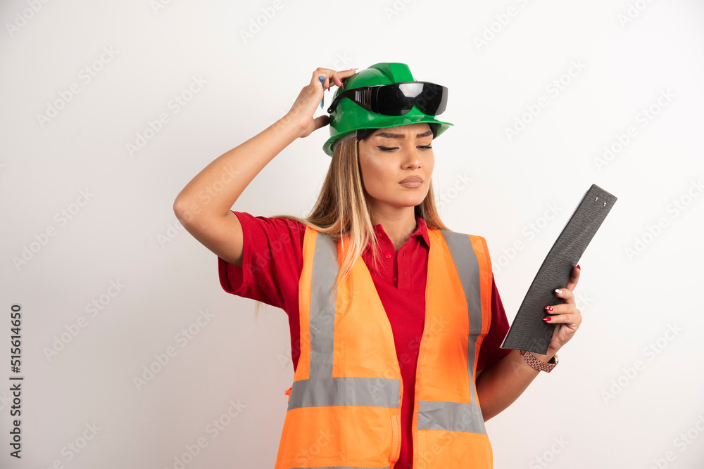 Worker woman industry in vest looking on clipboard Worker woman industry in vest looking on clipboard