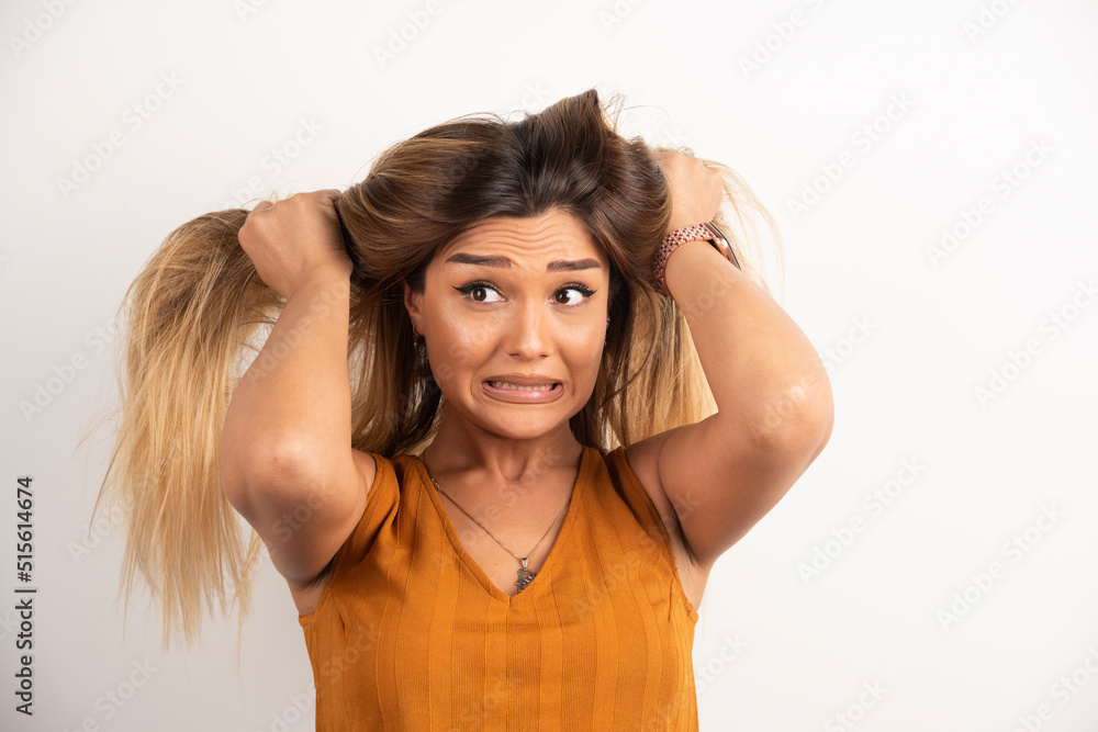 Young woman touching her hair and posing on white background Young woman touching her hair and posing on white background