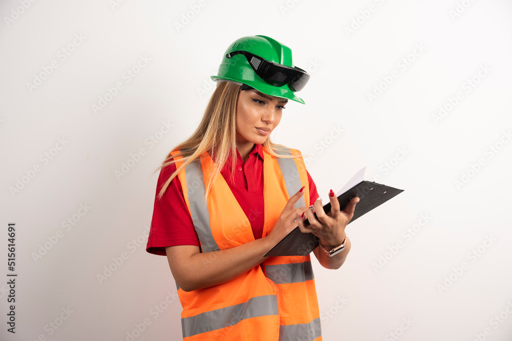 Worker woman industry in vest looking on clipboard Worker woman industry in vest looking on clipboard
