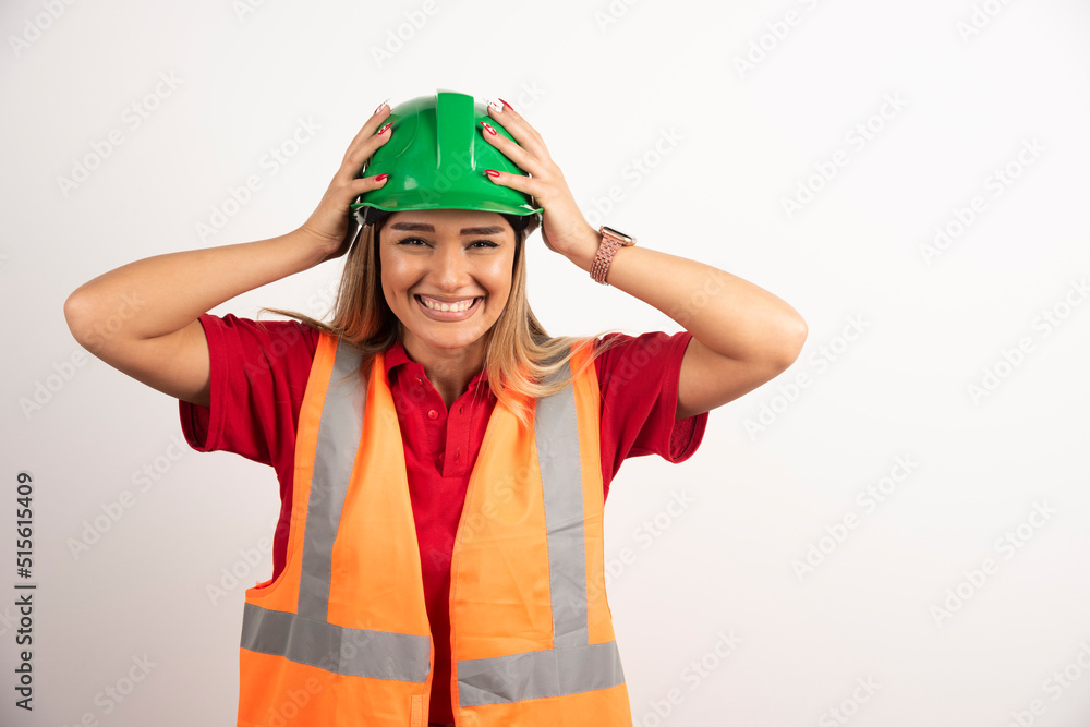 Smiling woman in protective uniform and helmet posing on white background