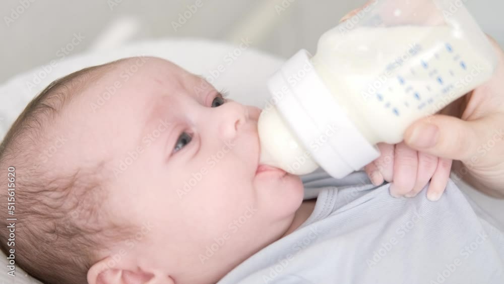loving mother feeding her little boy child with milk baby bottle at home, portrait infant Baby eating, drinking powdered milk loving mother feeding her little boy child with milk baby bottle at home, portrait infant Baby eating, drinking powdered milk