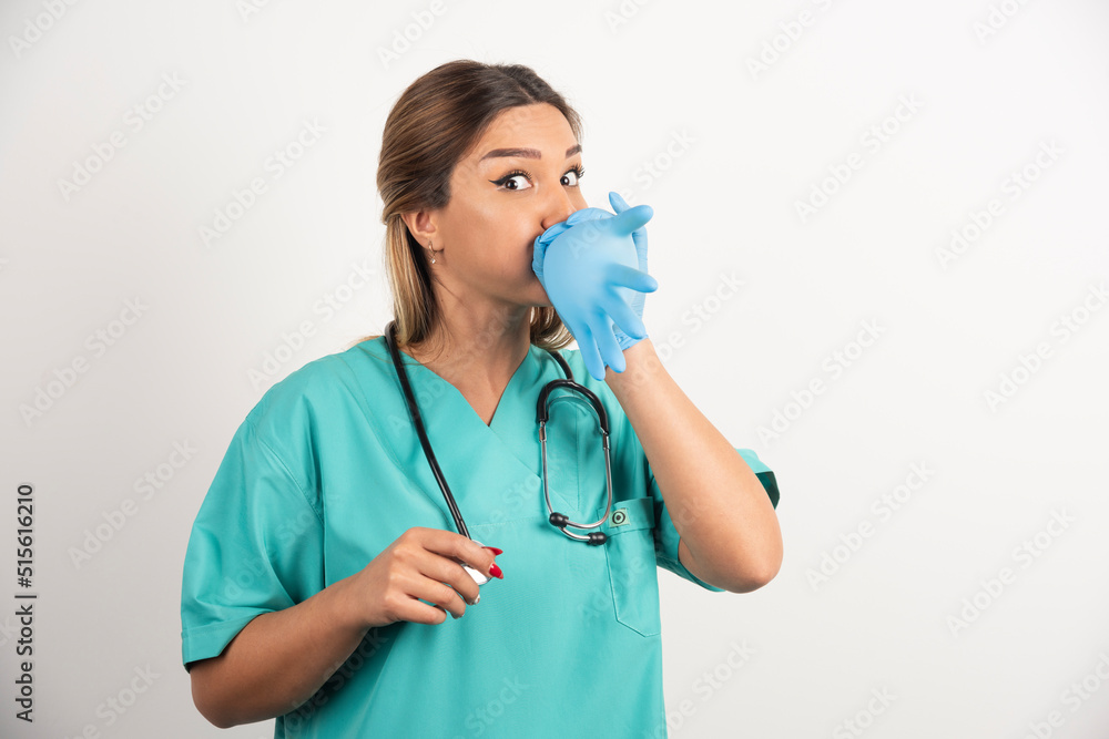 Young woman doctor wearing latex gloves and scrubs on white background Young woman doctor wearing latex gloves and scrubs on white background