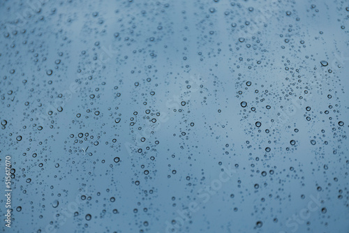 Blue raindrops on the window glass, selective focus.