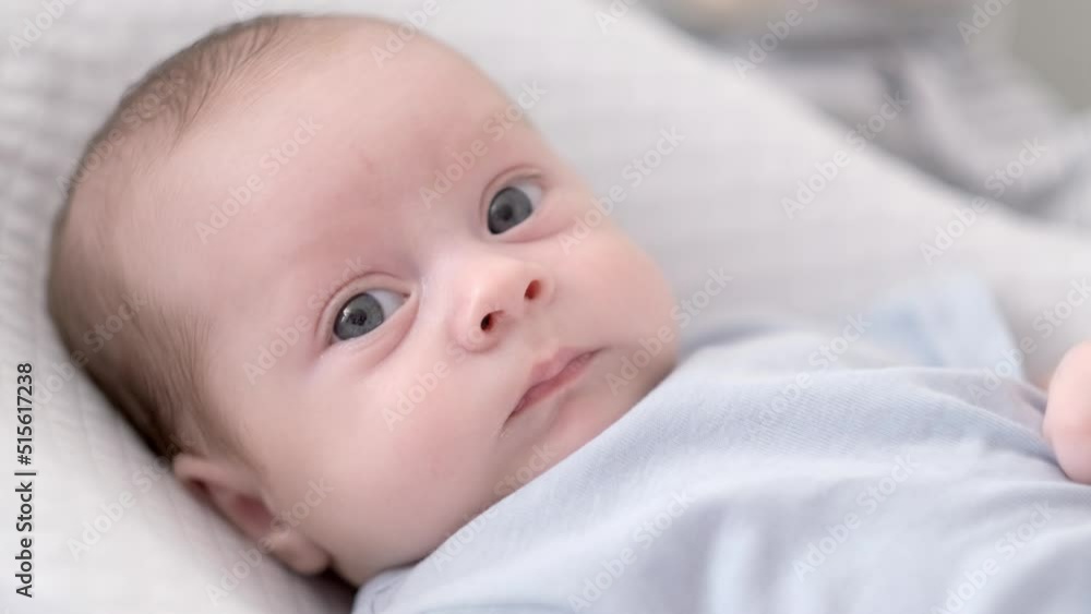 Portrait newborn baby boy lying in nursery cocoon with blue clothes on bed in bedroom at home, happy baby morning Portrait newborn baby boy lying in nursery cocoon with blue clothes on bed in bedroom at home, happy baby morning