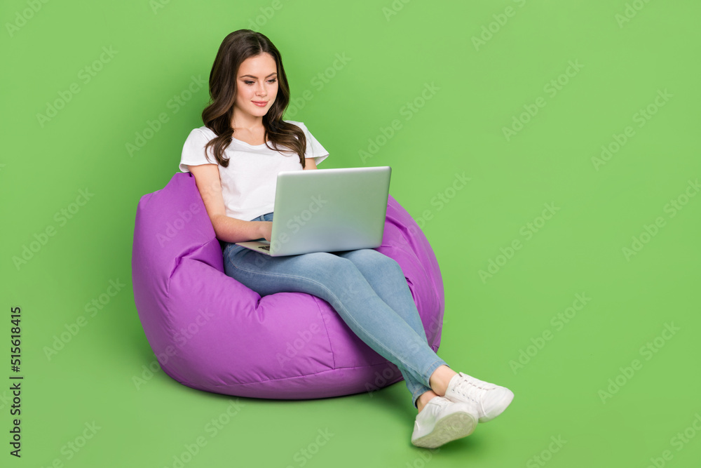 Photo of lovely charming woman dressed white t-shirt sitting bean bag typing gadget empty space isolated green color background Photo of lovely charming woman dressed white t-shirt sitting bean bag typing gadget empty space isolated green color background