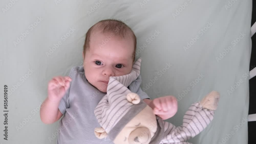 Newborn baby boy 3 months old lies in crib nursery with blue clothes on his back with teddy bear, looks at the camera, baby products concept, mock up Newborn baby boy 3 months old lies in crib nursery with blue clothes on his back with teddy bear, looks at the camera, baby products concept, mock up