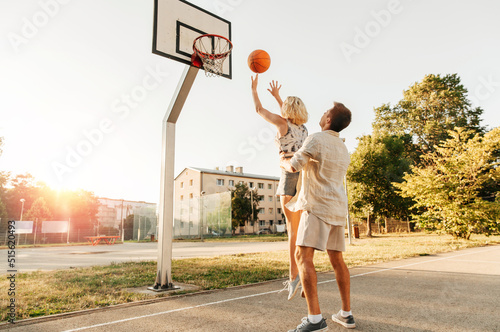summer holidays, sport and people concept - happy young couple with ball playing on basketball playground © Syda Productions