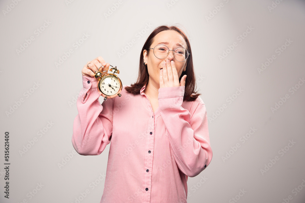 Young woman model holding an alarm clock on a white background Young woman model holding an alarm clock on a white background