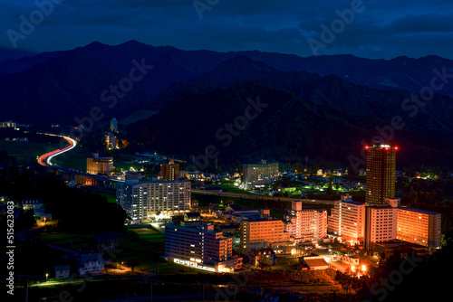 高層リゾートマンションが立ち並ぶ湯沢・岩原の夜景とS字カーブの高速道路を通る車のライト