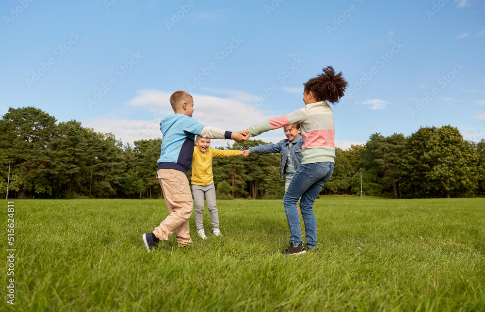 childhood, leisure and people concept - group of happy kids playing round dance at park childhood, leisure and people concept - group of happy kids playing round dance at park