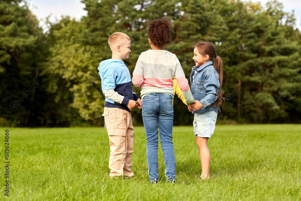 childhood, leisure and people concept - group of happy kids playing round dance at park childhood, leisure and people concept - group of happy kids playing round dance at park